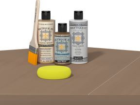 Retique It Barn Wood Kit with Light Wood Wood'n Primer, Barn Wood Gel Stain Alternative, Matte Polytique It topcoat, paintbrush, and yellow sponge on a tabletop.