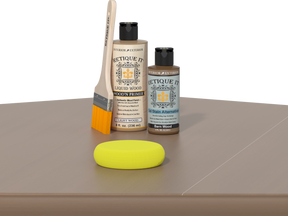 Retique It Barn Wood finishing kit with Liquid Wood Wood'n Primer, Barn Wood Gel Stain Alternative, paintbrush, and yellow sponge displayed on a barn wood surface.