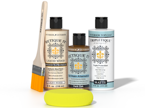 Retique It® Light Wood Wood’n Primer with Dark Oak Gel Stain Alternative, matte topcoat, brush, and yellow sponge on a dark tabletop.
