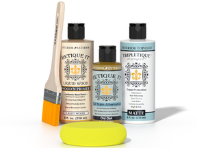 Retique It® Light Wood Wood’n Primer with Old Oak Gel Stain Alternative, matte topcoat, brush, and yellow sponge on a tabletop.