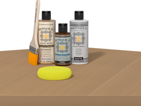 Retique It® Light Wood kit with brush, Pecan stain alternative, matte top coat, and yellow sponge on a wood surface.