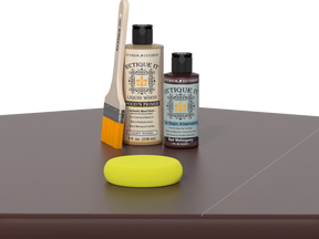 Retique It® Light Wood Wood’n Primer with Red Mahogany Gel Stain Alternative, brush, and yellow sponge on a tabletop.