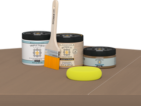 Retique It Barn Wood Kit with Matte Tripletique, Light Wood Wood'n Primer, Barn Wood Gel Stain Alternative, paintbrush, and yellow sponge on a tabletop.