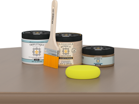 Retique It Barn Wood Kit with Satin Tripletique, Light Wood Wood'n Primer, Barn Wood Gel Stain Alternative, paintbrush, and yellow sponge on a tabletop.