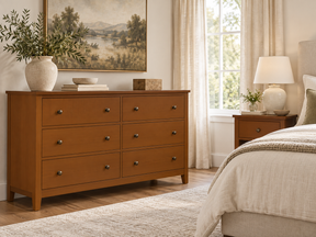 Traditional Cherry six-drawer dresser and matching bedside table in a softly lit bedroom with cream bedding.