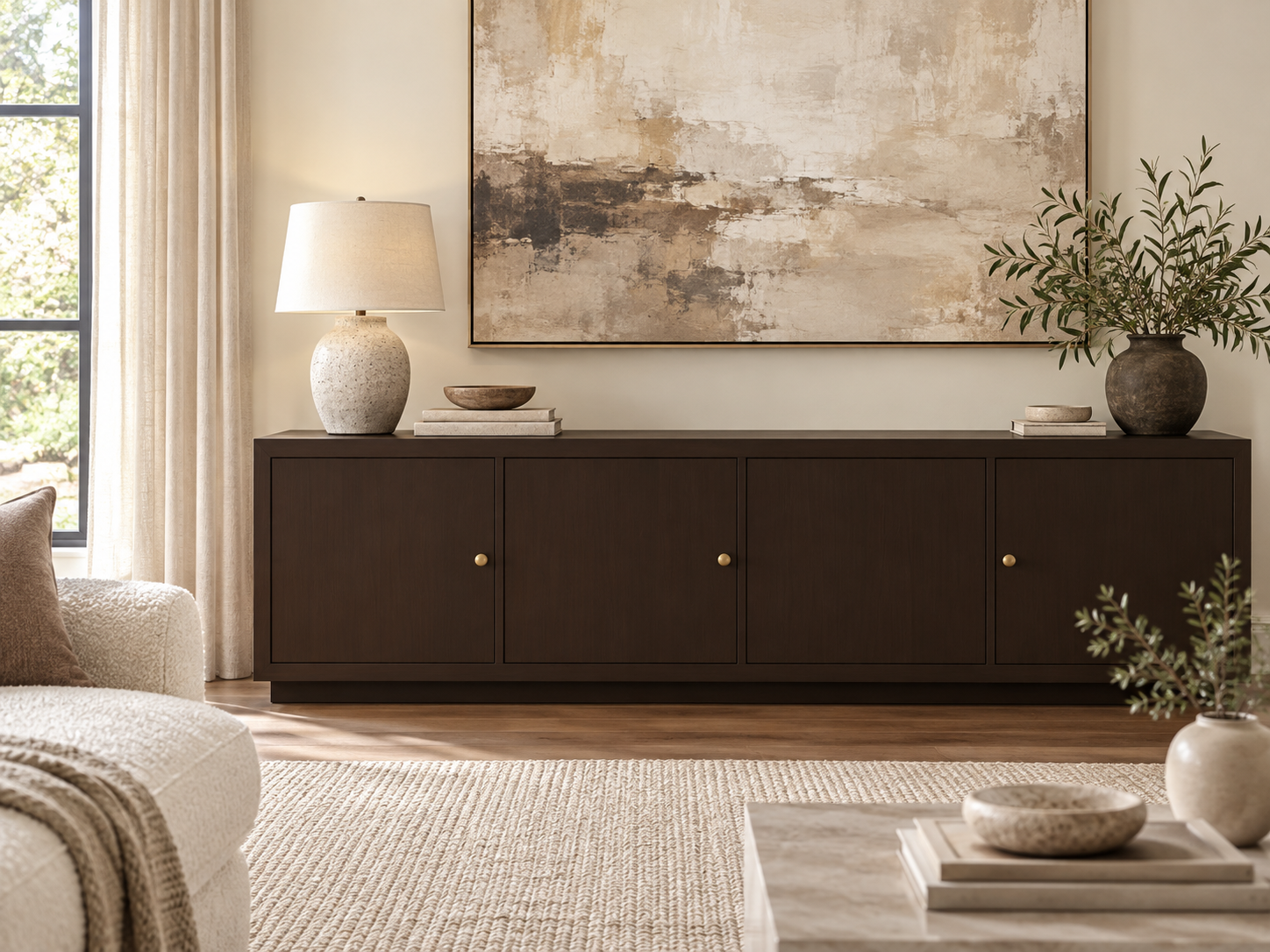 Dark Kona four-door sideboard with brass knobs in a neutral living room beneath abstract artwork.