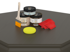 Painting supplies including jars, a brush, a sponge, and a roller on a dark surface.