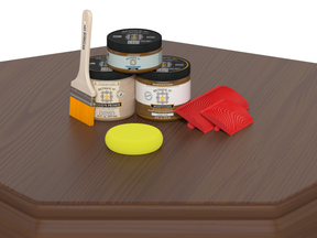 Woodworking tools including paintbrush, containers of wood primer, sanding block, and sanding blocks on a wooden surface.