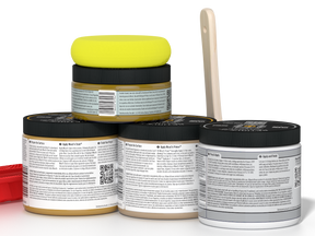 Four jars of a product with a yellow lid on top, a wooden tool beside them, on a white background.