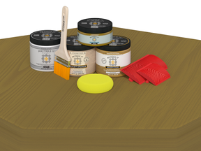 Collection of paint cans, brushes, and a sponge on a wooden surface