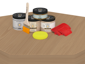 Painting supplies including cans, brushes, and a sponge on a wooden surface