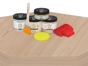 Painting supplies including cans, a brush, and sponges on a wooden surface.