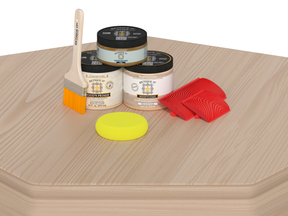 Woodworking kit with paint cans, a brush, and sandpaper on a wooden surface