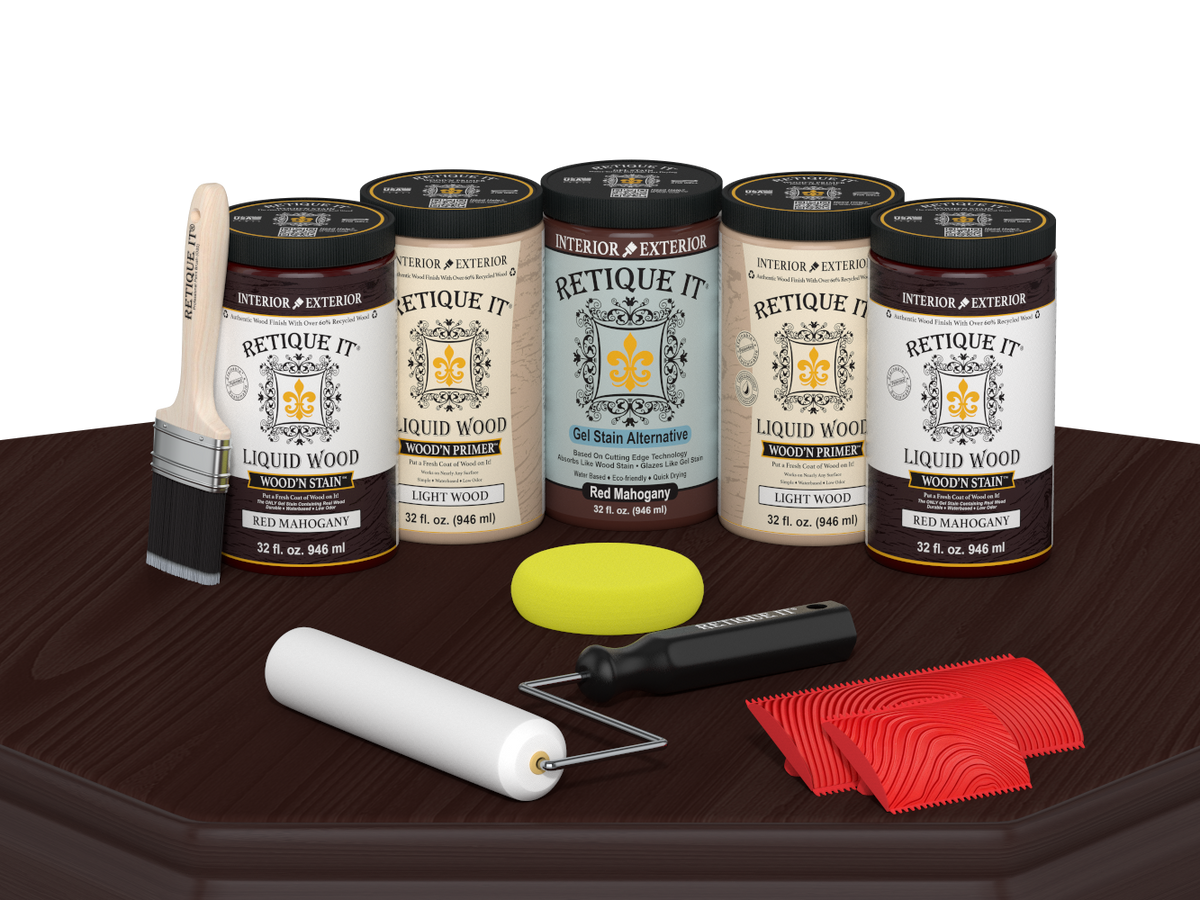 Retique It Red Mahogany Wood'n Kit featuring Red Mahogany Liquid Wood stain, Light Wood primer, Red Mahogany Gel Stain Alternative, paint brush, white roller, yellow sponge, and red graining tools displayed on a dark wood tabletop.