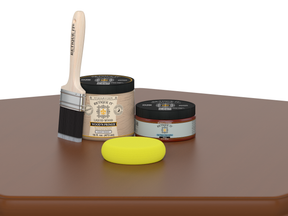 Paintbrush, wooden primer jar, and yellow sponge on a brown surface with a white background