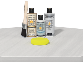 Set of Etiquette It! wood care products including bottles, a brush, and a yellow sponge on a white surface.